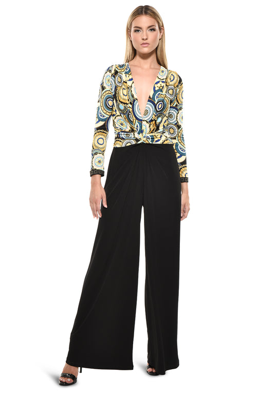 Model wearing Julian Chang Amber Jumpsuit in Contrast/Versus print, featuring a plunging V-neckline, long sleeves, and black draped pants
